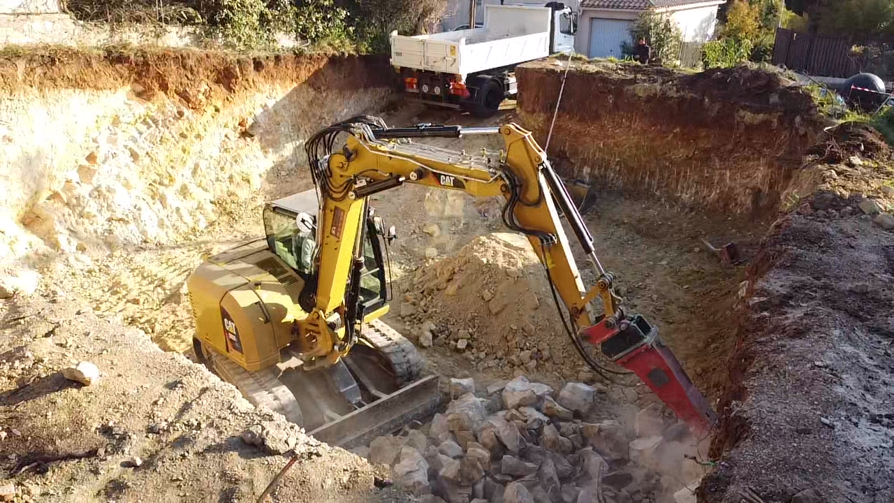 Pelle CAT avec brise-roche en chantier d'aménagement